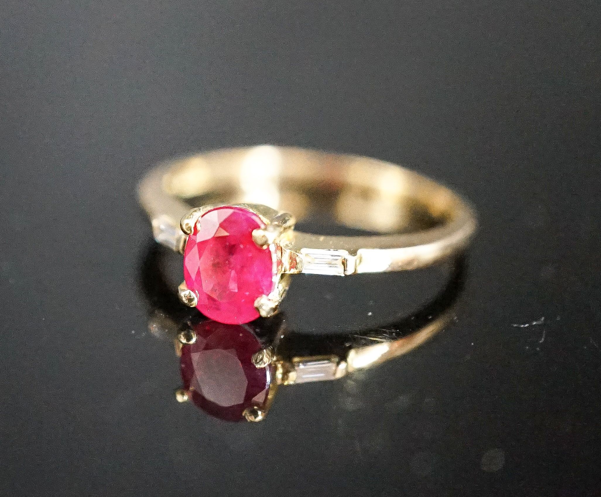 A modern 18ct gold and single stone oval cut ruby ring, with diamond set shoulders, size O, gross weight 2.7 grams.